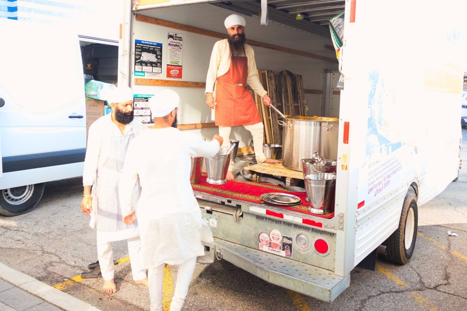 Sevadar serving dal from a large pot in a truck